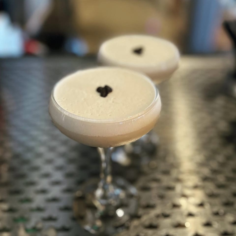 Two espresso martinis with coffee-bean garnish on a bar counter.